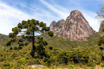Fototapeta premium Valley view with Tres Picos rocky mountains, Salinas State Park, with famous climbing paths, sunny day with few clouds, Teresopolis, Rio de Janeiro, Brazil