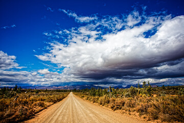 Straight dirt road with storm clouds