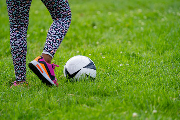 Low section of girl playing soccer on grass - obrazy, fototapety, plakaty