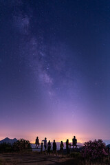 Grupo de personas observando la Via Lactea encima de la ciudad