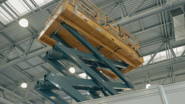 Yellow color new modern telescopic aerial platform lifts workers to work at heights, is presented at the exhibition. Shot in motion
