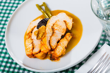 Plate of appetizing baked turkey breast with prunes and spicy sauce