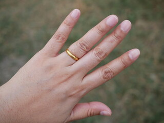 female finger wearing a gold ring.