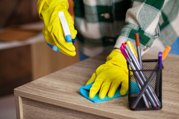Professional cleaning lady cleans table using a sponge and spray