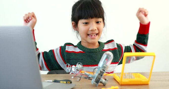 The little girl asian building robotic car in science lesson in the house . Which increases the development and enhances learning skills gifted brilliant children working with technology.