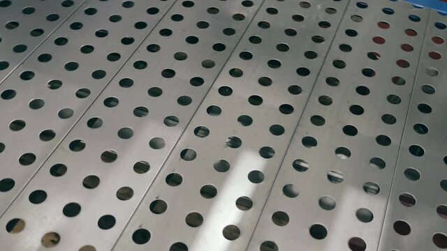 Perforated metal sheets, divided into sections - the basis of warehouse shelves - shine beautifully in the light. Shot in motion. Closeup