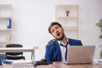 Fototapeta premium Young male employee unhappy with excessive work in the office