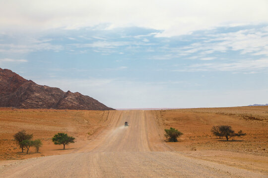 View of a distant vehicle driving a lonely desert road