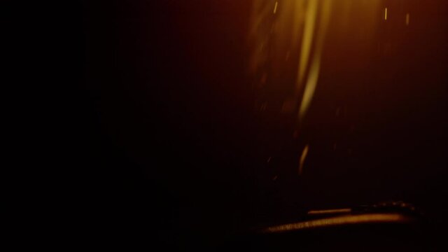 SLOW MOTION, MACRO, DOF: Detailed close up shot of sparks flying as person ignites a lighter. Macro view of a vintage steel lighter ignited in dark. Orange flame rises from a lighter lit up at night.