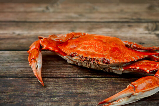 Steamed crab with grass on a wooden surface.