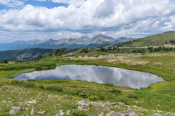 Fototapeta premium Summer Mountain Pond - A panoramic view of a small pond at summit of Cottonwood Pass, surrounded by high peaks of Sawatch Range, on a calm Summer day. Buena Vista - Crested Butte, Colorado, USA.