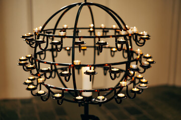 Fototapeta na wymiar Votive candles stand on a ball-shaped stand in a church