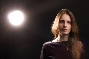 Studio portrait of a young woman on black background with a back light