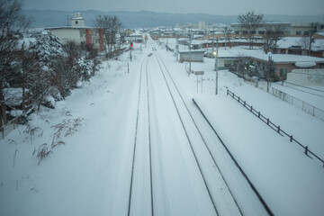 Obraz premium 雪の積もった線路と街の景色