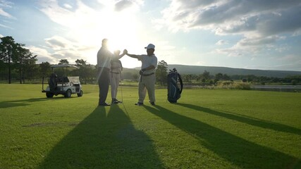Group of Asian people businessman and senior CEO enjoy outdoor sport lifestyle golfing together at golf country club. Healthy men golfer shaking hand after finish game on golf course at summer sunset