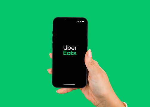Female hand holding a smartphone iPhone 13 Pro with Uber Eats app on the screen. Green background. Rio de Janeiro, RJ, Brazil. January 2022