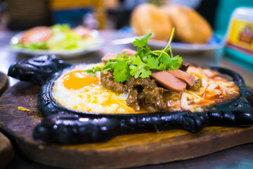 Beef jerky and fried eggs with sausages and salads are served on a black stone plate