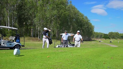 Group of Asian people businessman and senior CEO enjoy outdoor sport golfing together at country club. Healthy men golfer holding golf bag walking on fairway with talking together on summer vacation