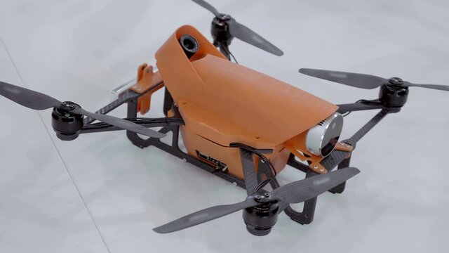 Modern orange quadcopter with high definition video camera. Shot in motion