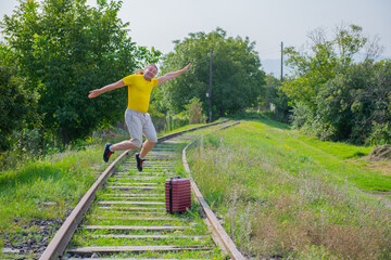 in white shorts a man with a suitcase jumps on the railroad