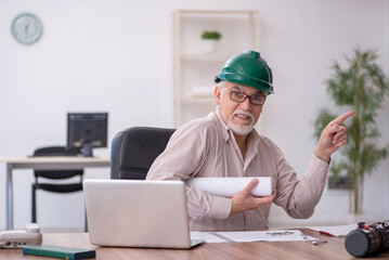 Old male architect working in the office