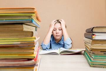 bored purposeful child reading a book studying grammar preparing for school and exams.reading books in the library. Stacks of books on a bookshelf