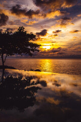 Fototapeta na wymiar Sunset at the edge of a swimming pool at Kata beach in Phuket province, in Thailand