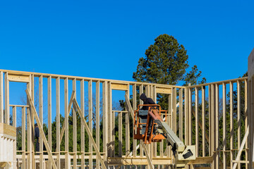 Close up of a worker in white protective gloves holding plank installing it on household construction using air hammer in nailing wooden beams.