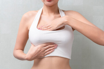 Woman hand checking lumps on her breast cancer for signs of breast cancer on background. Healthcare concept.
