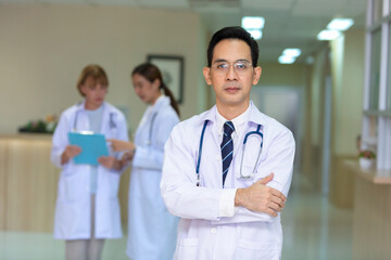 Portrait of the young Specialist Doctor wearing a stethoscope while standing with crossed arms and looking away by Confident.