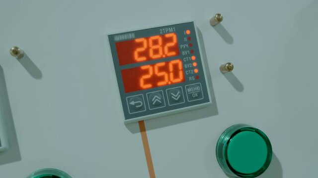 Digital temperature controllers with red indication, green luminous lamps, indicating normal operation and continuation of technological processes in industrial equipment. Shot in motion. Closeup
