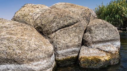 Huge boulders on the banks of the Nile. Close-up. Rough surface. The texture of the stone. Green reeds against a blue sky. Egypt