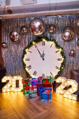 Glowing inscription 2022 with gifts and clock on background