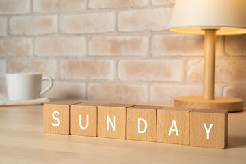 「SUNDAY」と書かれた積み木とコーヒーカップ、テーブルランプ
