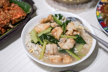 Hainanese chicken rice (Steam chicken with rice) with vegetable closeup on a plate and broth.