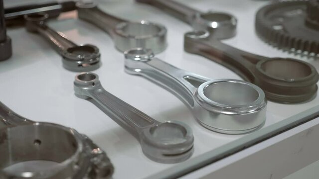 New connecting rods for different engines lie side by side in the window and shine with their edges in the light - sale of spare parts in the store. Shot in motion. Closeup