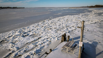 Picnic bench on a dock with a view over a frozen lake
