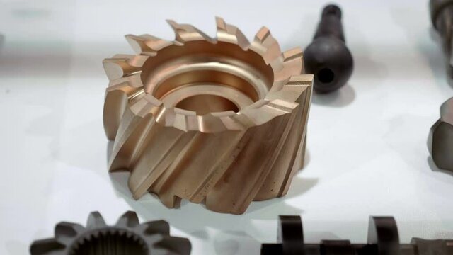 New bronze helical gear on a showcase as a spare part for industrial equipment or a car gearbox. Shot in motion. Closeup