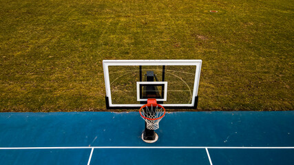 Front view of transparent basketball hoop on blue court © Nealj121