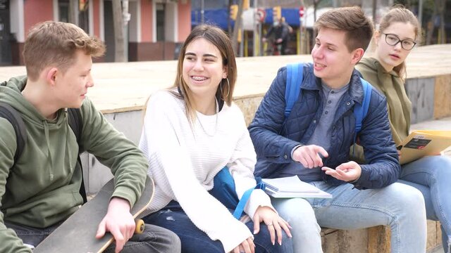 Cheerful teenagers sitting together, talking and having fun outdoors 