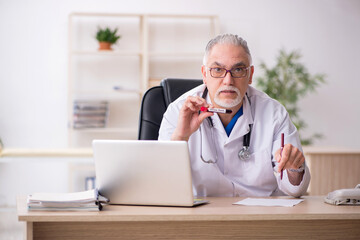 Obraz premium Old male doctor chemist in coronavirus concept