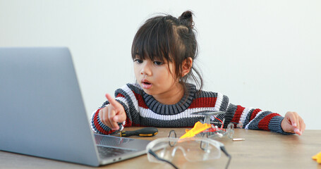 The little girl asian building robotic car in science lesson in the house . Which increases the...
