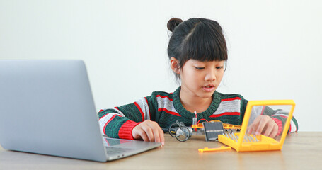 The little girl asian building robotic car in science lesson in the house . Which increases the development and enhances learning skills gifted brilliant children working with technology.