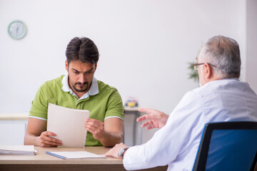 Obraz premium Young man visiting old male doctor
