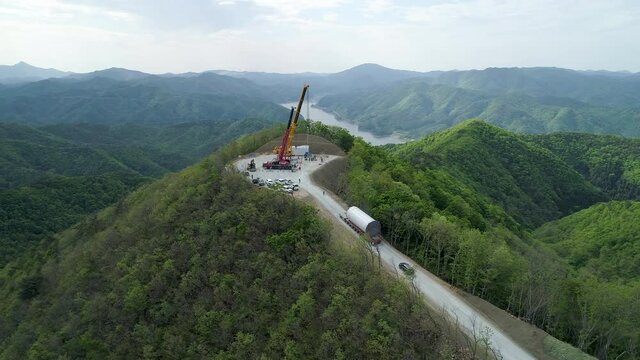 Wind power generator pillars are being transported along the road in the forest. 풍력발전기 운송, 풍력발전기 기둥.
