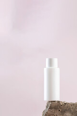 White empty bottle of cosmetics on a concrete podium on a pink background close-up. Copy space.