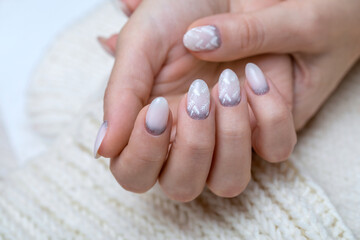 Drawing on the nails with white leaves and silver glitter. Winter topical manicure for a woman....