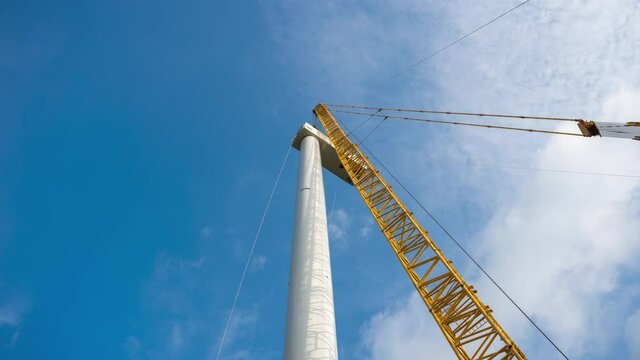 Construction of a wind power generator for renewable energy, Turbine hangs on crane hook at wind turbine construction site. Timelapse. 풍력발전기, 풍력터빈 설치, 신재생에너지.