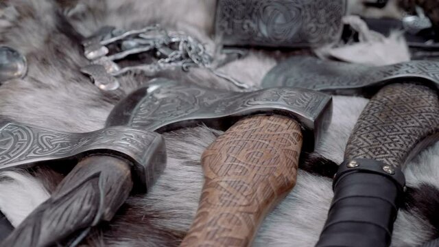 Many different beautiful axes in a retro style and in a similar entourage lie on the skin of a killed animal. Shot in motion. Closeup
