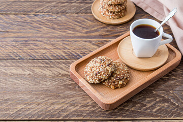 Diet biscuits made of oatmeal with sesame and flax seeds are served for breakfast on a wooden tray with freshly ground coffee.